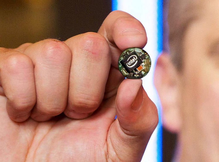 Man pinching an Intel Curie IoT device with his pointer finger and thumb.