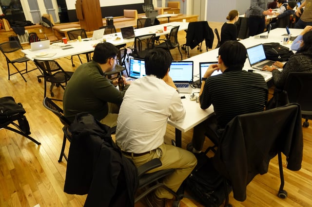 Three men programming on laptops during Hack Night at Union Hall.