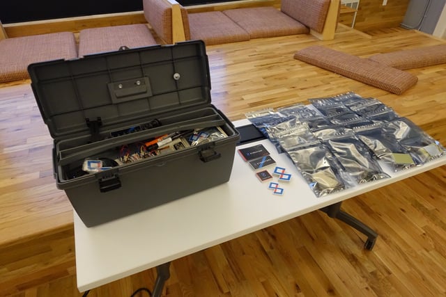 A table with a box full of supplies next to Losant IoT merchandise.