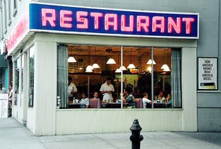 Old corner diner with a red neon sign that says restaurant.