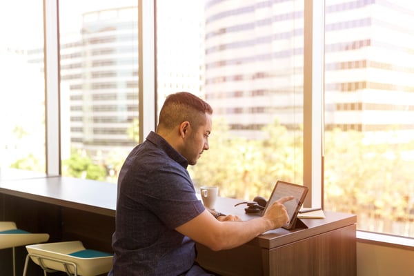 Man near window viewing and touching a digital tablet