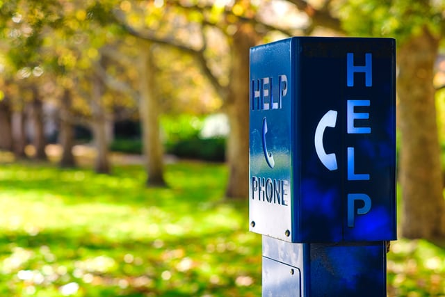 blue emergency phone with grass and trees in the background