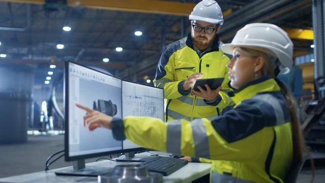 Male and female manufacturers looking at computer screen. Female is pointing.