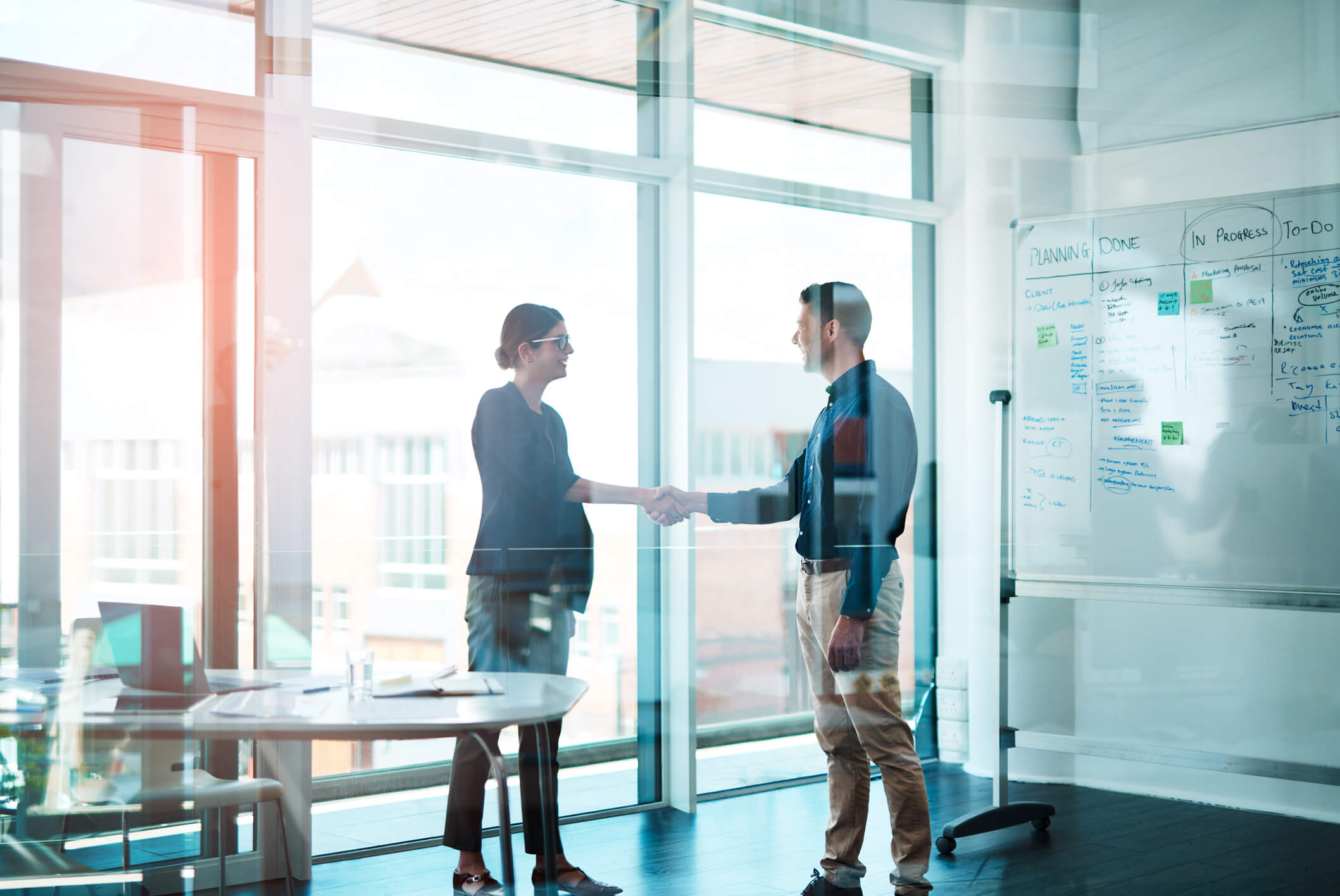 people shaking hands in a glass conference room