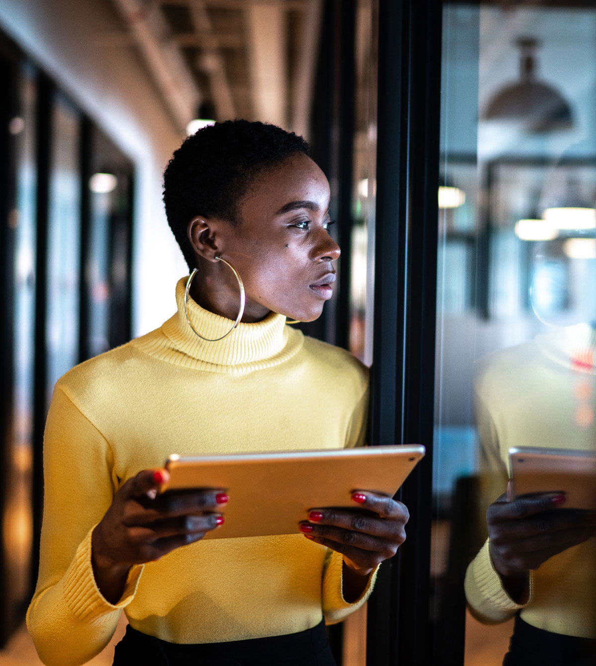 Young-business-woman-using-digital-tablet-and-looking-away-in-an-office-tall